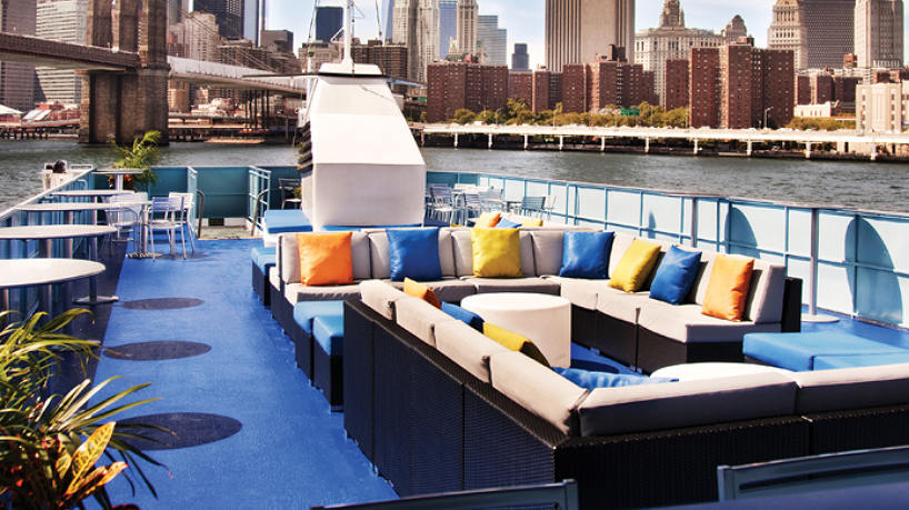 Rooftop yacht lounge with cushioned seating and city skyline views.